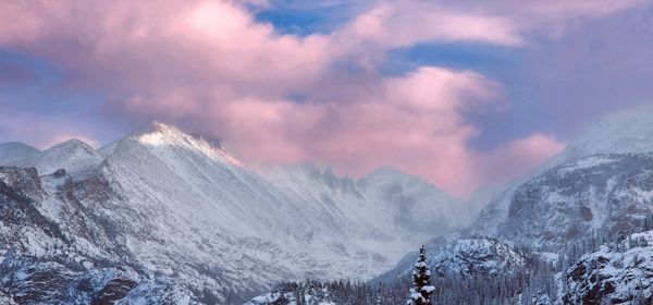 Panoramic view of majestic snow-capped mountains under a vibrant sky with pink and purple clouds