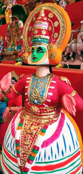 Vibrant Kathakali-style doll with green face, elaborate headdress, and colorful traditional costume from India